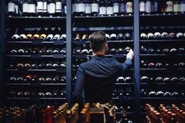 man grabbing bottle from wine storage in liquor store