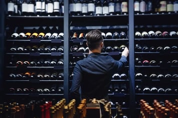 man grabbing bottle from wine storage in liquor store