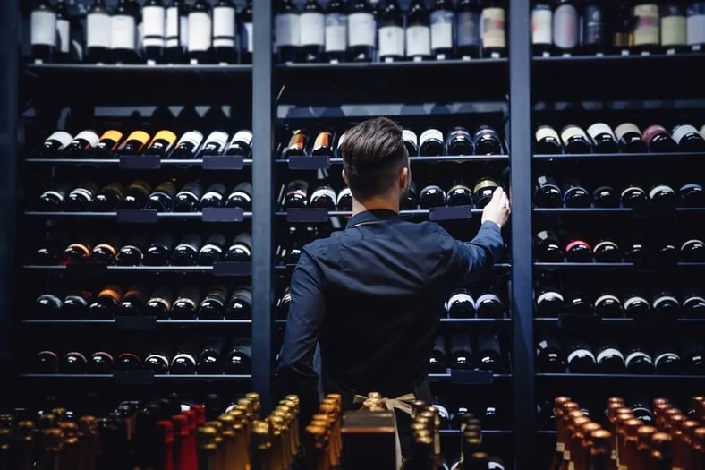 man grabbing bottle from wine storage in liquor store